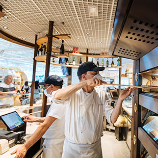 Un pizzaiolo inforna una pizza all&rsquo;interno del ristorante Eataly.
